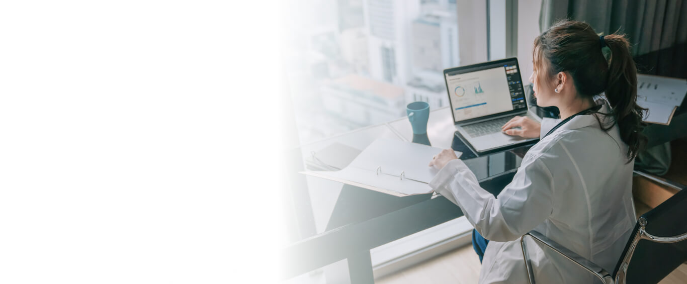 doctor working at desk with notepad and computer